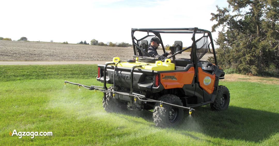Sprayer demonstration with spray reaching across gravel lot from UTV
